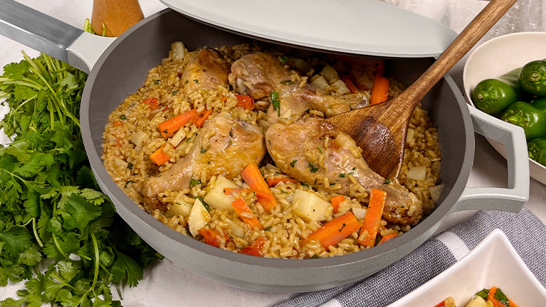 Chicken and rice inside the Pan in gray with the spoon and garnish on the side