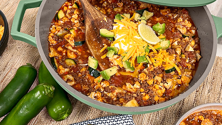 Chili Faux Mac inside of The Pan in green topped with cheddar cheese and lemon