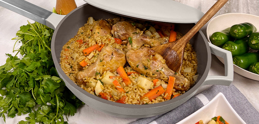 Chicken and rice inside the Pan in gray with the spoon and garnish on the side
