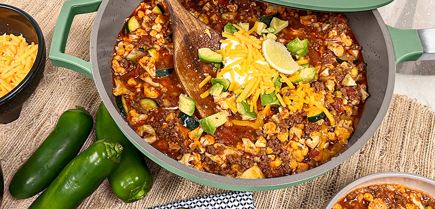 Chili Faux Mac inside of The Pan in green topped with cheddar cheese and lemon